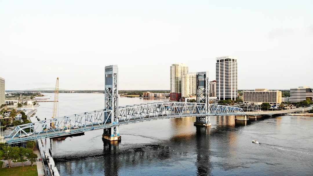 Jacksonville, FL by Jax Facts a bridge spanning over a river with a city in the background